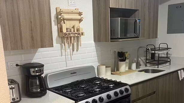 A modern kitchen with a stove, microwave, and wooden cabinets.