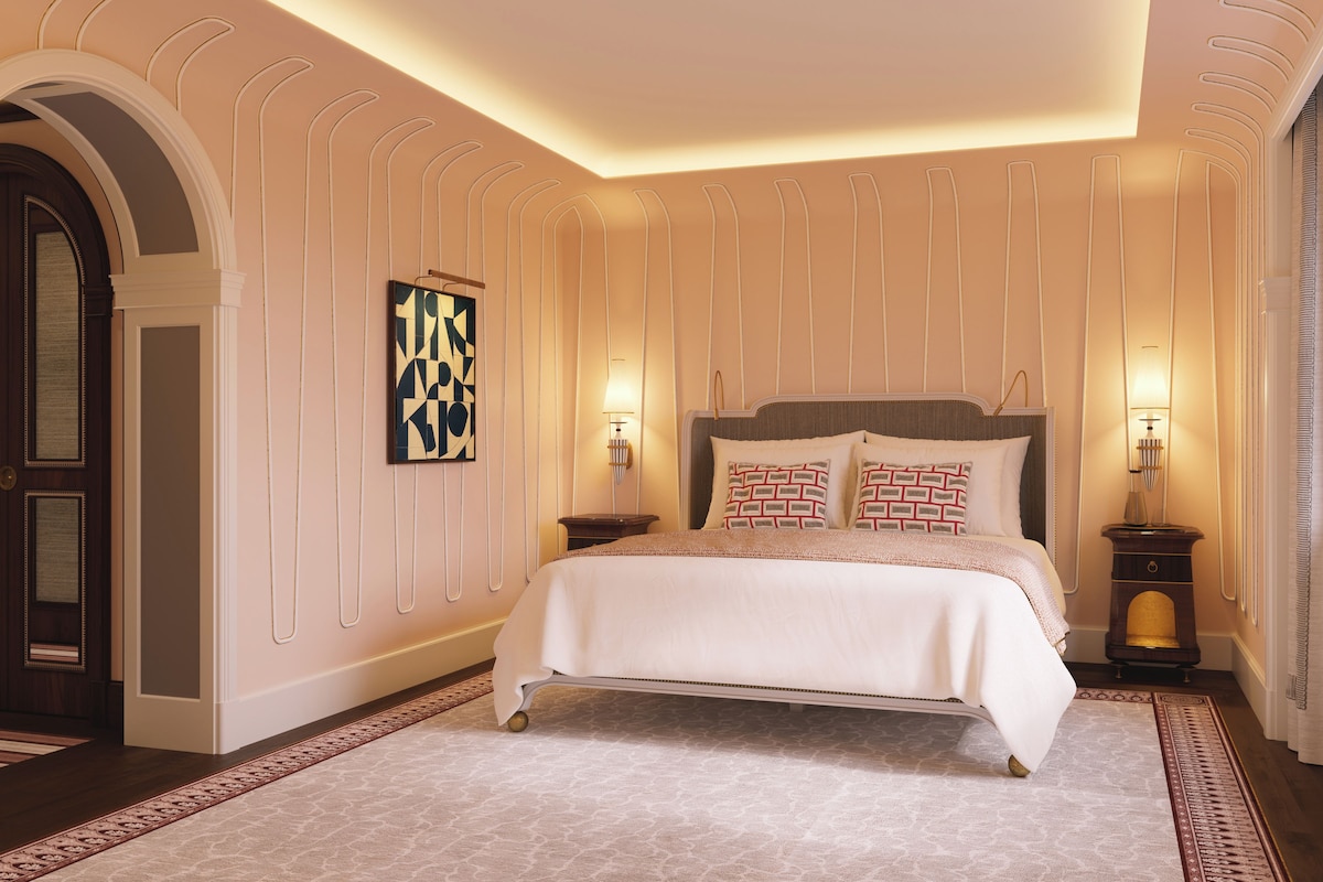 A hotel room with a large bed, a decorative wall panel, and a patterned rug.