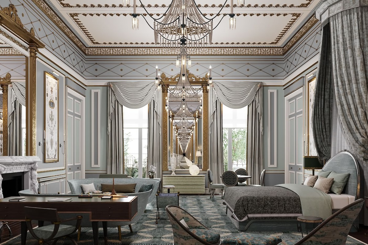 A luxurious bedroom with a large bed, a sitting area with a table and chairs, a chandelier, and a view of the outdoors.