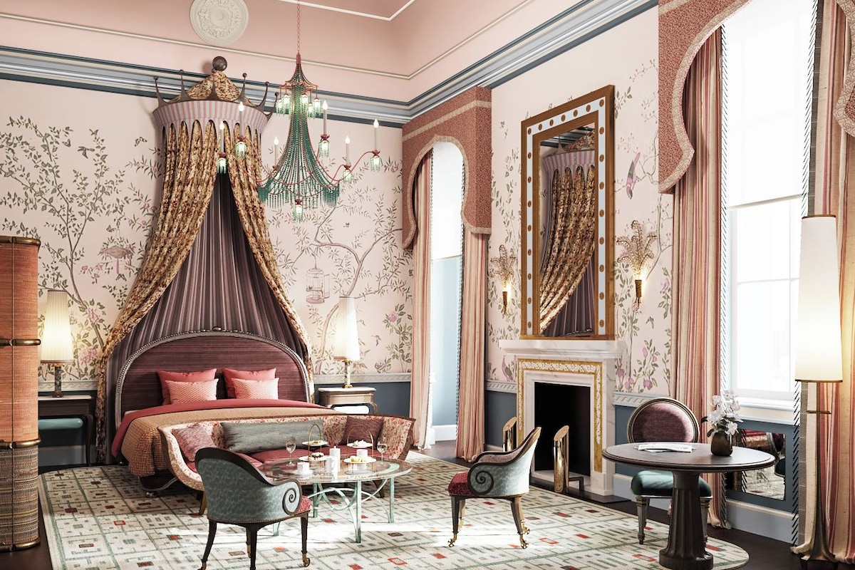 A luxurious bedroom with a canopy bed, a sitting area with a table and chairs, and a large mirror.