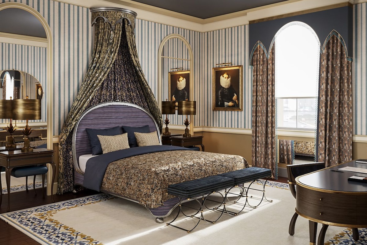 A bedroom with a canopy bed, a round table, and a large window.