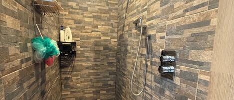 Une douche avec un mur carrelé, un pommeau de douche et un flexible de douche.