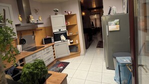 A modern kitchen with a skylight, wooden cabinets, a refrigerator, and a dining area with a table and chairs.