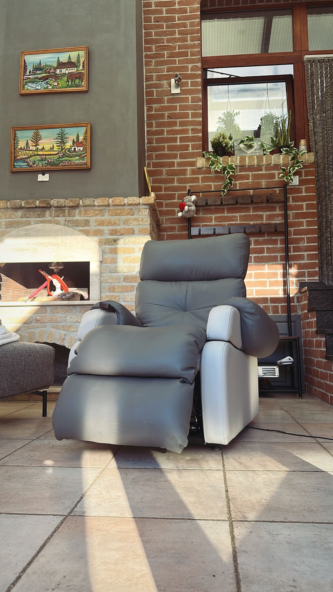 Un espacio al aire libre moderno con un sillón reclinable gris, una mesita y una chimenea.