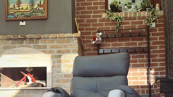 Un espacio al aire libre moderno con un sillón reclinable gris, una mesita y una chimenea.