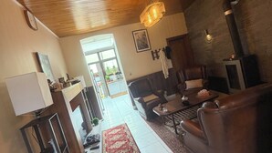 A spacious living area with a wooden ceiling, a fireplace, a sofa, and a dining table.
