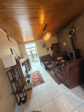Un salón amplio con techo de madera, chimenea, sofá y mesa de comedor.