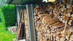 A covered outdoor area with stacks of firewood and a metal roof.