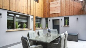 A covered patio with a dining table and chairs, wooden beams, potted plants, and a door. - Relaxing time-out on approx. 100sqm in an idyllic location with a large covered terrace (Jühnde)
