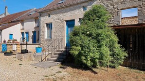 A stone building with a blue door, steps leading to the entrance, and a small tree in the foreground. - Holiday Home 'Chez Pauline' with Private Garden (Massangis)
