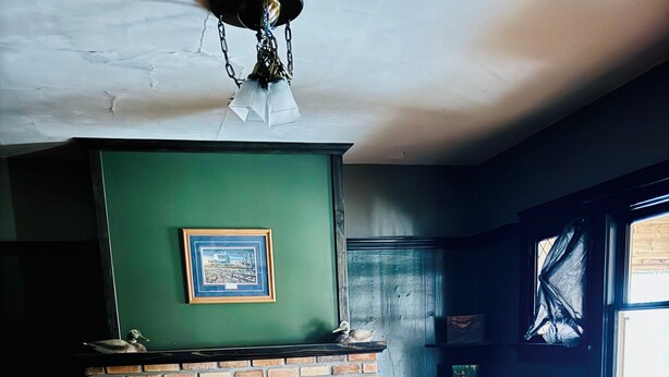 Een gezellige woonkamer met een metselwerk open haard, een lijst met een foto erboven en een raam met gordijnen.