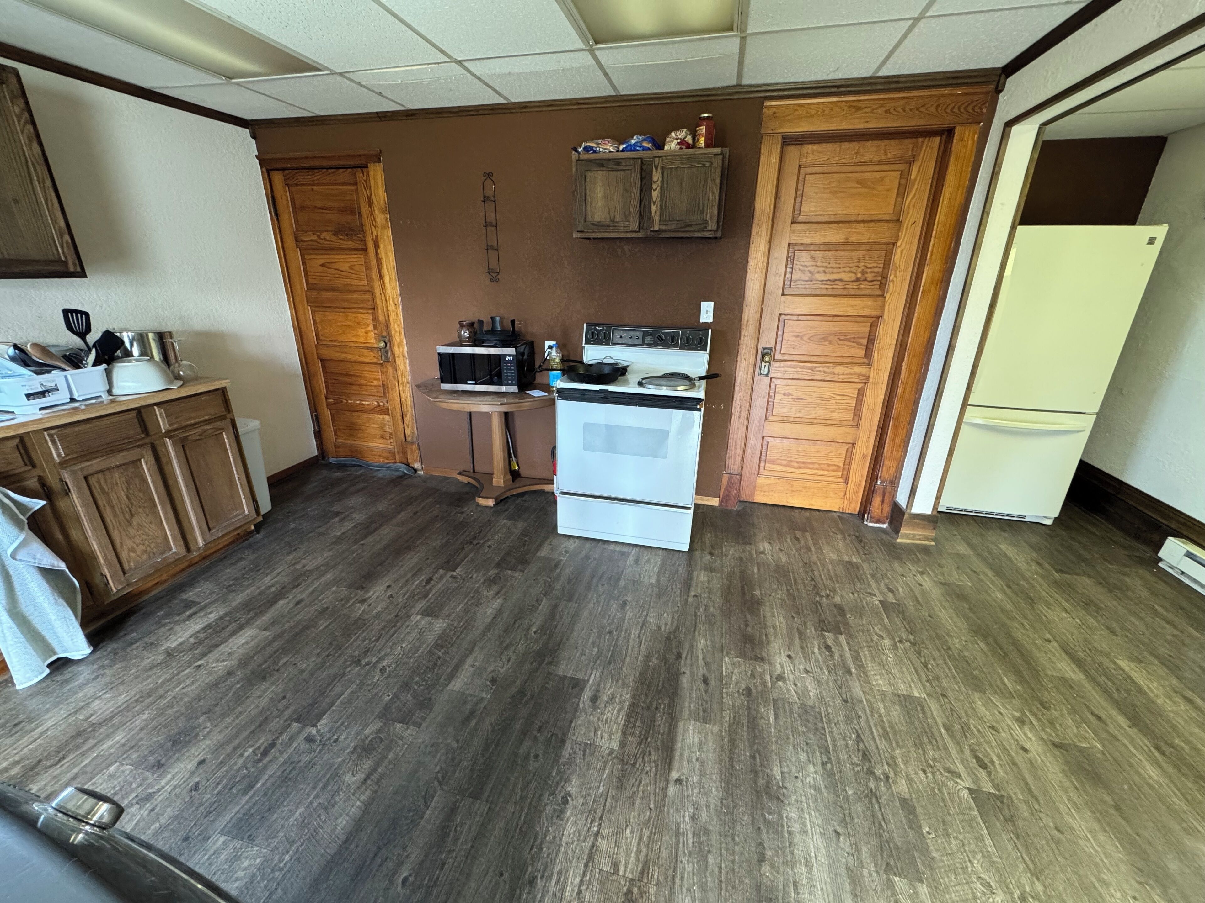 A compact kitchen with wooden cabinets, a white stove, and a microwave on a small table.