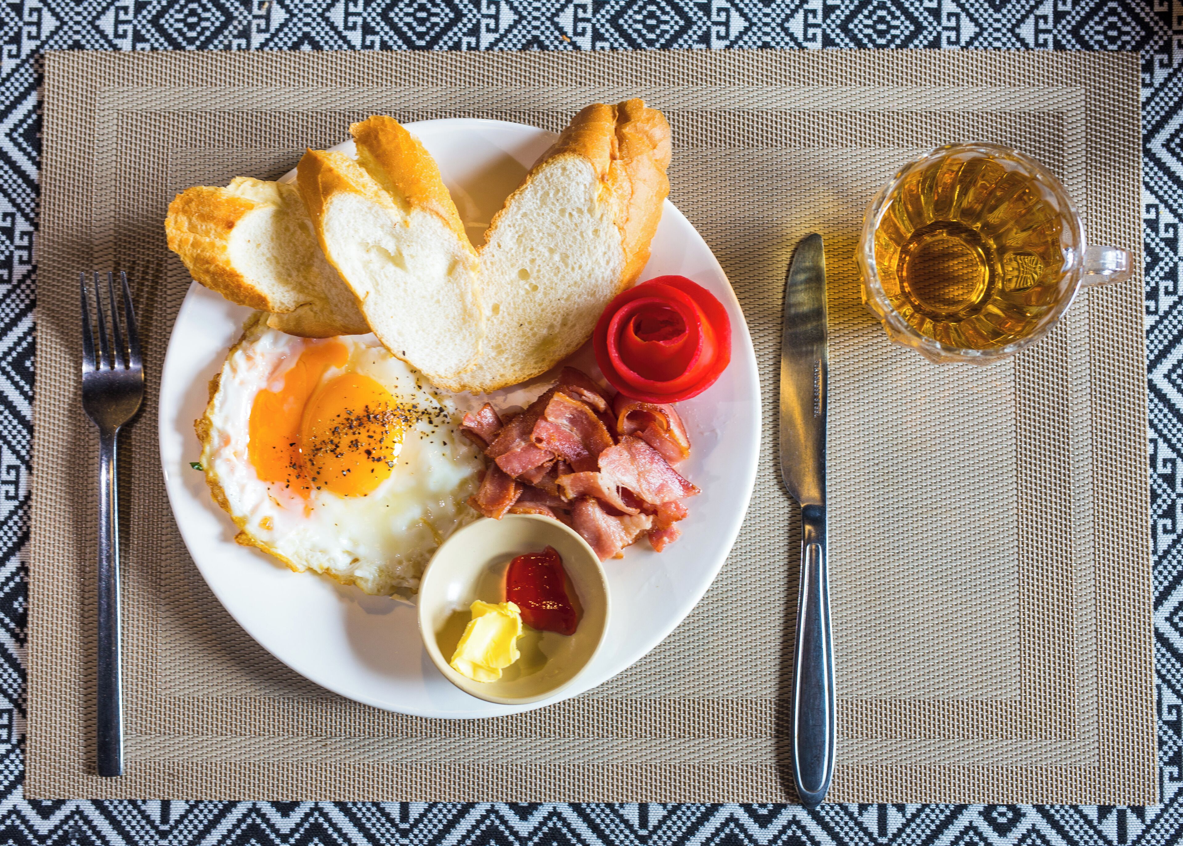 Een bord met eieren, bacon, toast, en een klein schaaltje boter en jam.