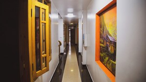 A hallway with a wooden door, a white wall with a framed picture, and a black and white floor. - Sapa Central House (Sa Pa)