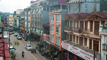 A street view with buildings, parked motorcycles, and cars.