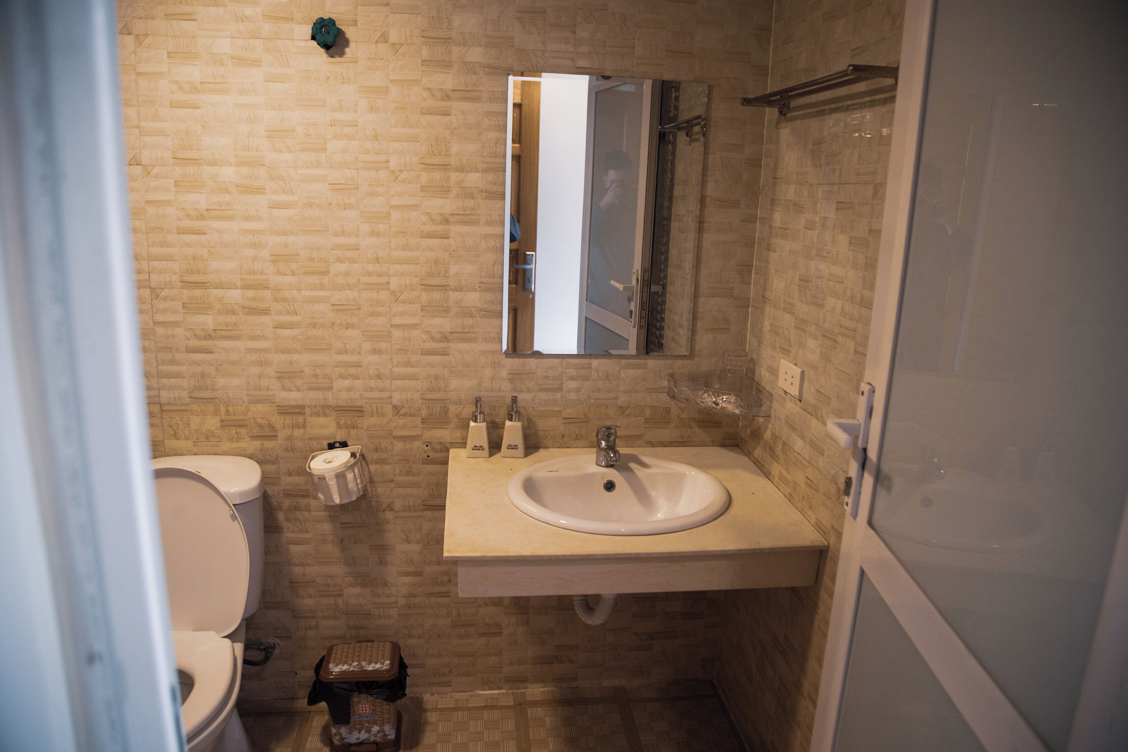 A bathroom with a toilet, sink, and mirror.