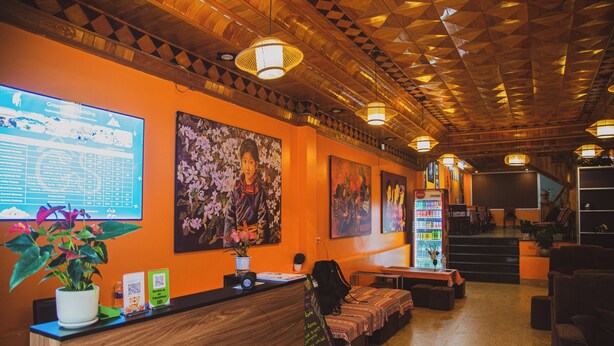 A reception area with a wooden reception desk, seating area, and a staircase leading upstairs. - Sapa Central House (Sa Pa)