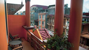 A balcony with a view of colorful buildings, a table with chairs, and a potted plant. - Sapa Central House (Sa Pa)