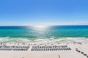 A beach with rows of sun loungers and umbrellas, a sandy shore, and the ocean. - NEW LISTING❄️Tidewater 906❄️Gulf Front-Heated Indoor Pool-Hot Tub-Fitness Center (Panama City Beach)