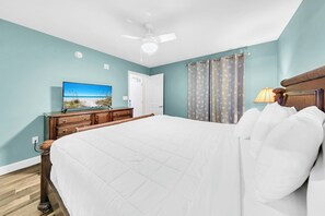 A bedroom with a large bed, a ceiling fan, a dresser, a television, and a door. - NEW LISTING❄️Tidewater 906❄️Gulf Front-Heated Indoor Pool-Hot Tub-Fitness Center (Panama City Beach)