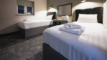 Habitación de hotel con dos camas, un escritorio, cafetera y espejo.