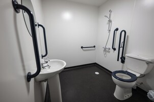 Un baño pequeño y moderno con un lavamanos blanco, inodoro y ducha.