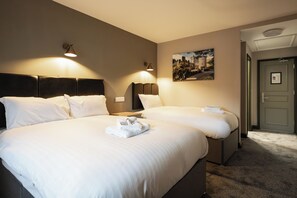 A hotel room with two beds, a headboard, wall-mounted lamps, a framed picture, and a door. - Pairc House Hotel (Birmingham)
