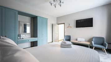 A hotel room with a large bed, a desk with a chair, a TV, and a wardrobe.