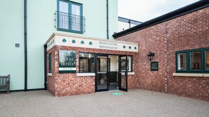 The exterior of the Irish Centre Birmingham, featuring a brick facade, a welcoming entrance with glass doors, and a signboard indicating the name and location. - Pairc House Hotel (Birmingham)