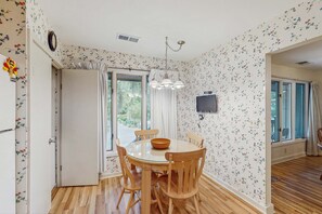 A dining area with a round table, wooden chairs, a bowl, and a chandelier. - Scenic-view cottage with sunroom, deck, kitchen & pool - close to beach & golf (Kiawah Island)