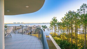 A balcony with a view of the marina and water, surrounded by greenery and a clear sky.