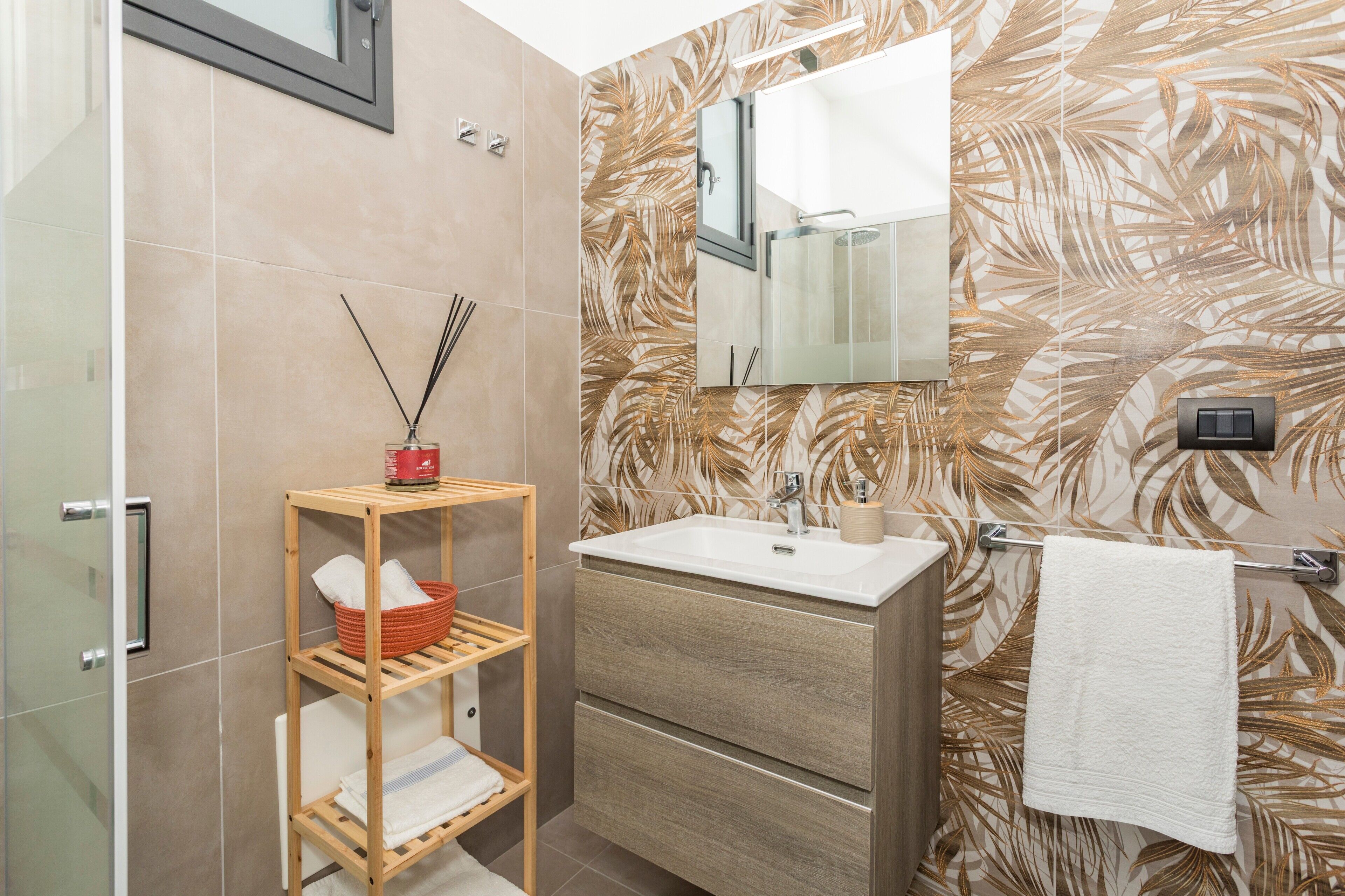 A bathroom with a wooden shelf, a sink, a mirror, and a towel rack.