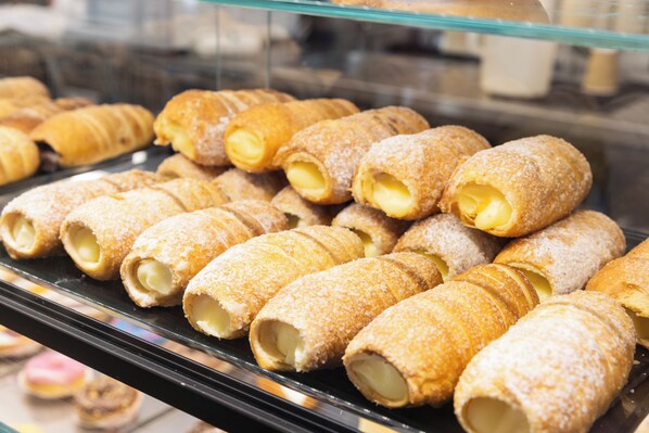 A display case with various pastries, including cream-filled rolls and other baked goods. - Aima Boutique Rooms (Costa Volpino)