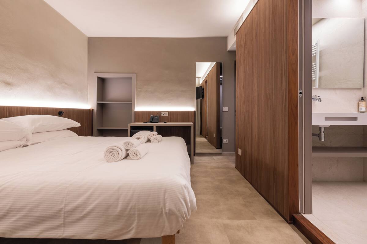Une chambre d’hôtel comprenant un lit, une table de chevet, un miroir et une armoire.