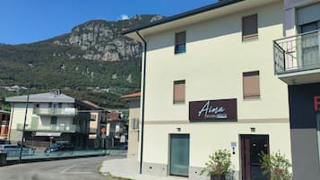 A building with a sign for 'Aina Boutique Rooms' on a street with a mountain in the background.