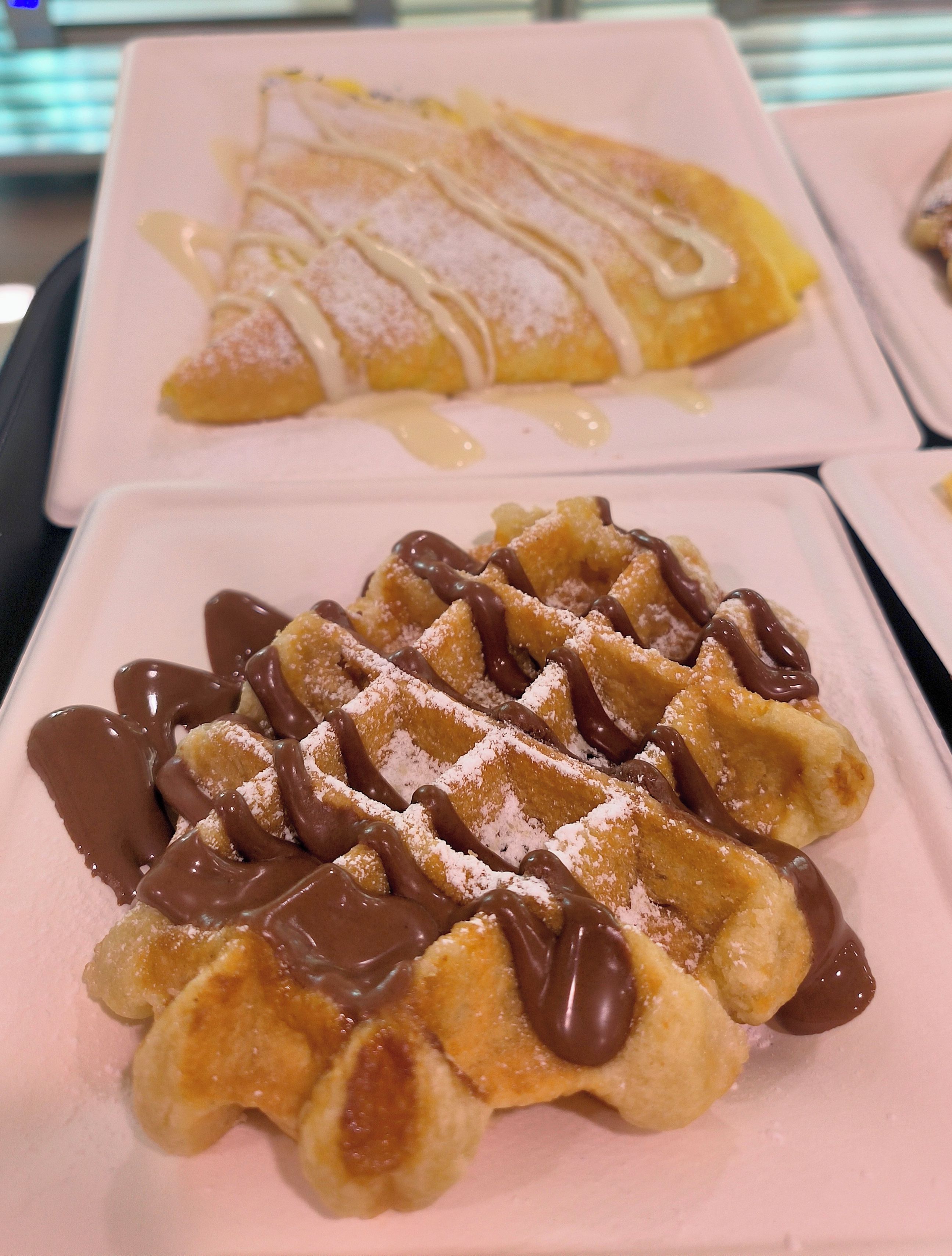 Ein Teller Waffeln mit Schokoladensauce und Puderzucker.