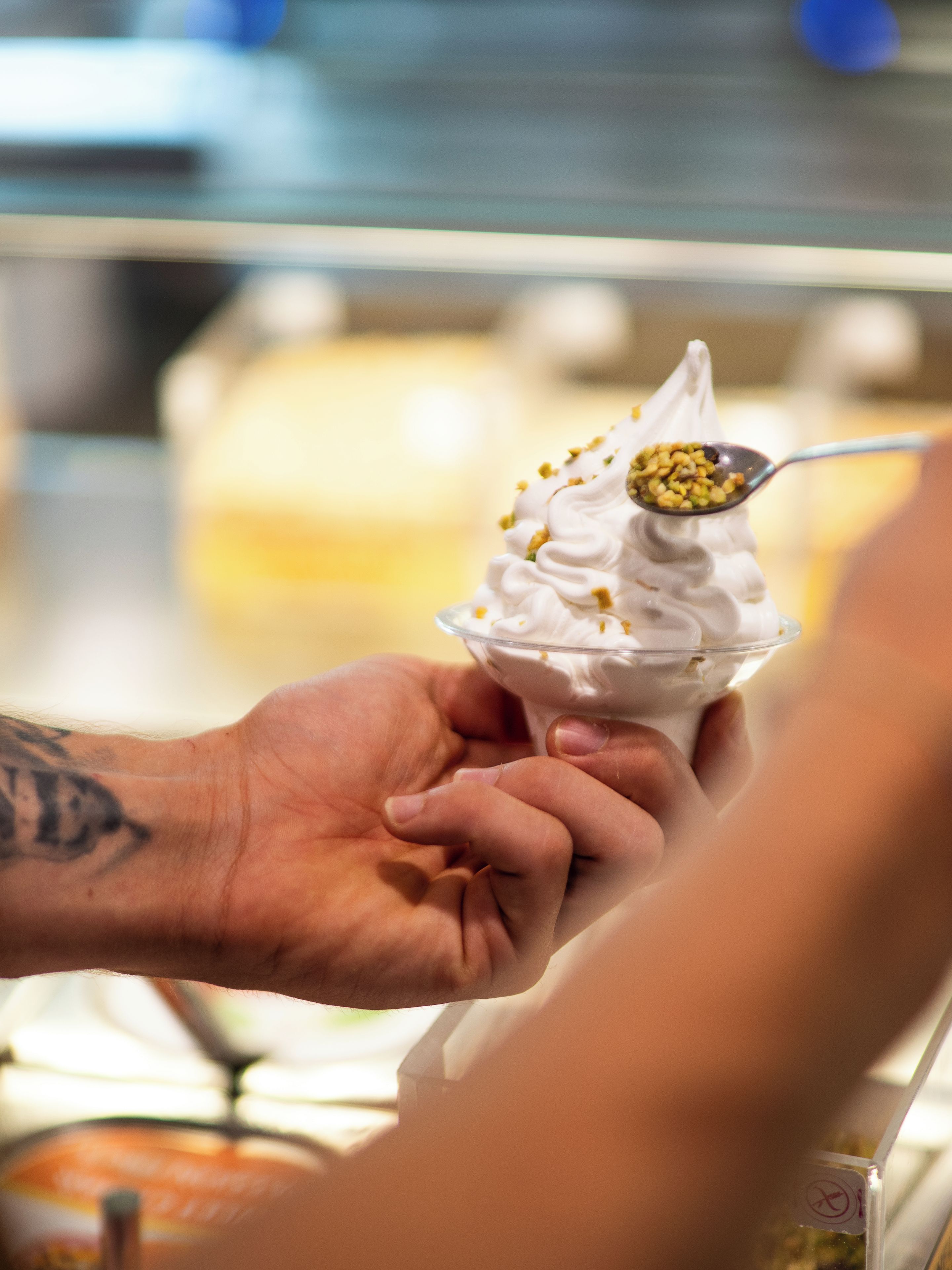 A close-up of a hand holding a spoon with a scoop of ice cream.