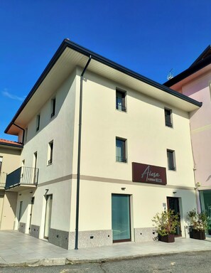 Un immeuble de deux étages, avec une enseigne indiquant « Aima Boutique Rooms » au rez-de-chaussée.