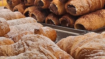Exposição de doces, incluindo croissants e doces recheados com chocolate, em uma padaria.