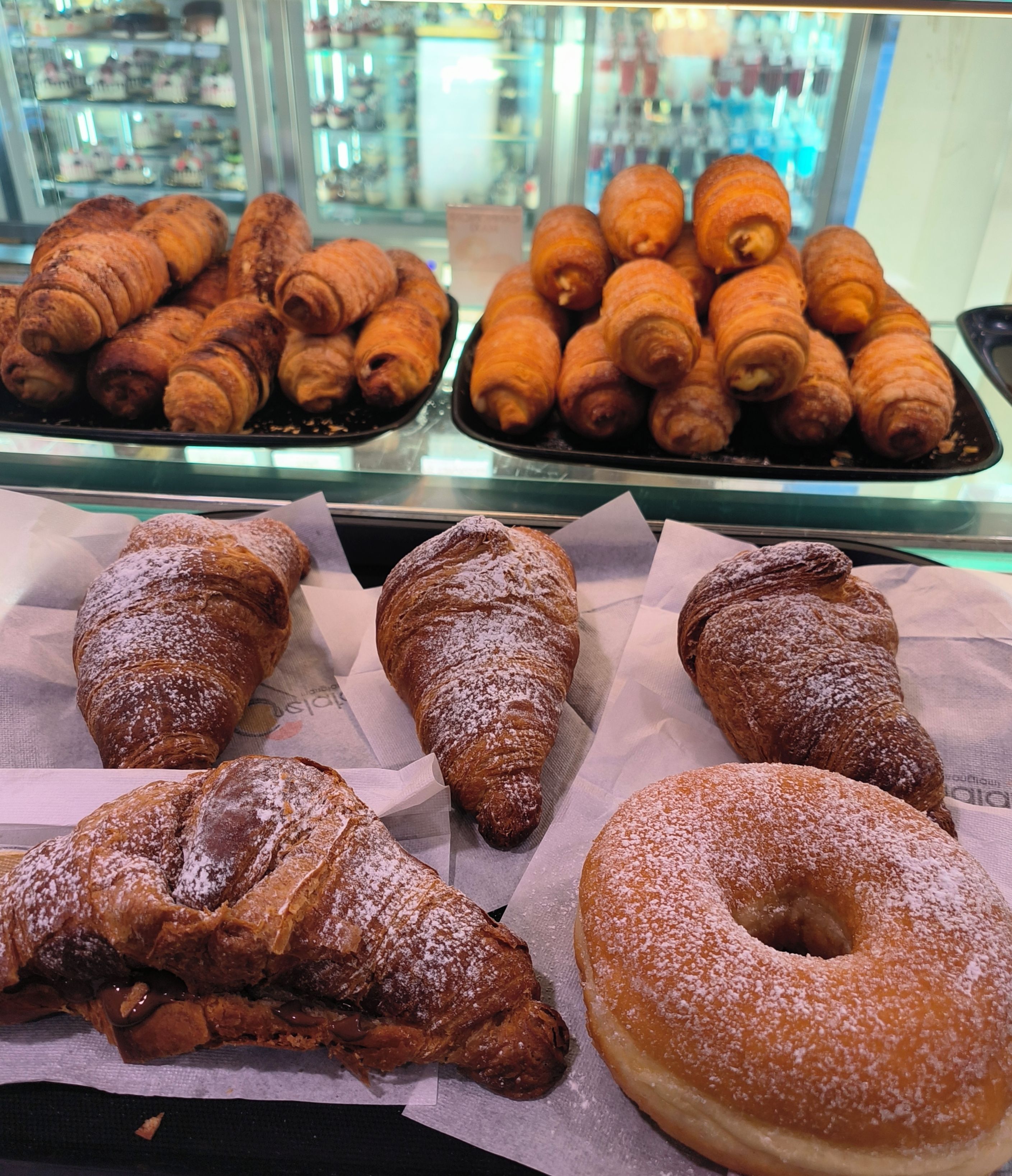 Una selezione di dolci tra cui croissant e una ciambella.
