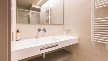 Un baño moderno con un lavamanos blanco, un espejo y un perchero para toallas.