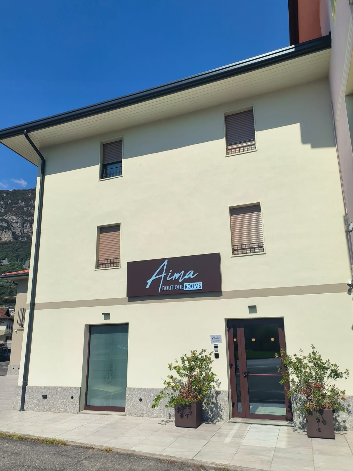 Un bâtiment dont la façade porte une enseigne indiquant « Aima Boutique Rooms ».