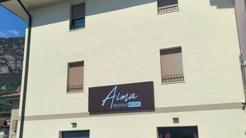Un bâtiment dont la façade porte une enseigne indiquant « Aima Boutique Rooms ».