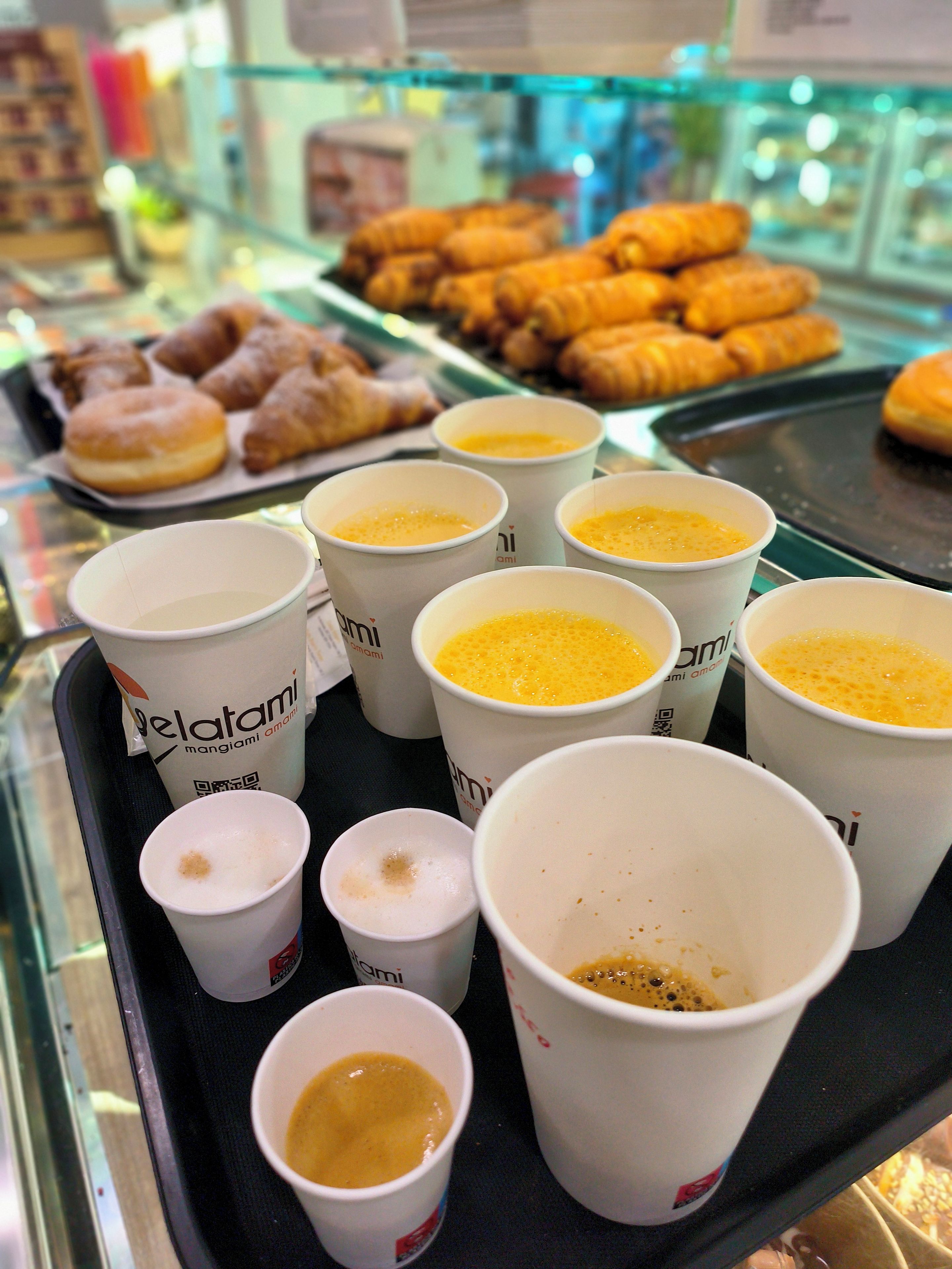 Una bandeja con varias tazas de café y una variedad de pasteles.