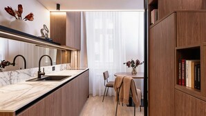 Una cocina moderna con encimera de mármol, armarios de madera y un comedor con una silla y una mesa.