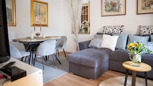 A modern living room with a grey sofa, a dining table with chairs, and artwork on the walls. - Ca' Dij Noni (Valle San Nicolao)