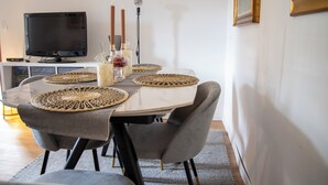 A dining area with a round table, grey upholstered chairs, and woven placemats. - Ca' Dij Noni (Valle San Nicolao)