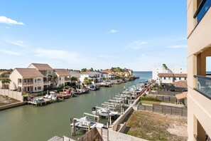 A marina with boats docked, waterfront buildings, and a clear view of the sea.