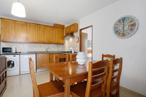 Une cuisine avec des meubles de rangement en bois, un four à micro-ondes, un évier et une table à manger avec des chaises.