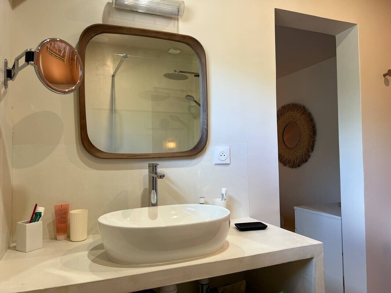 Een badkamer met een ronde spiegel, een wit wastafel en een handspiegel.